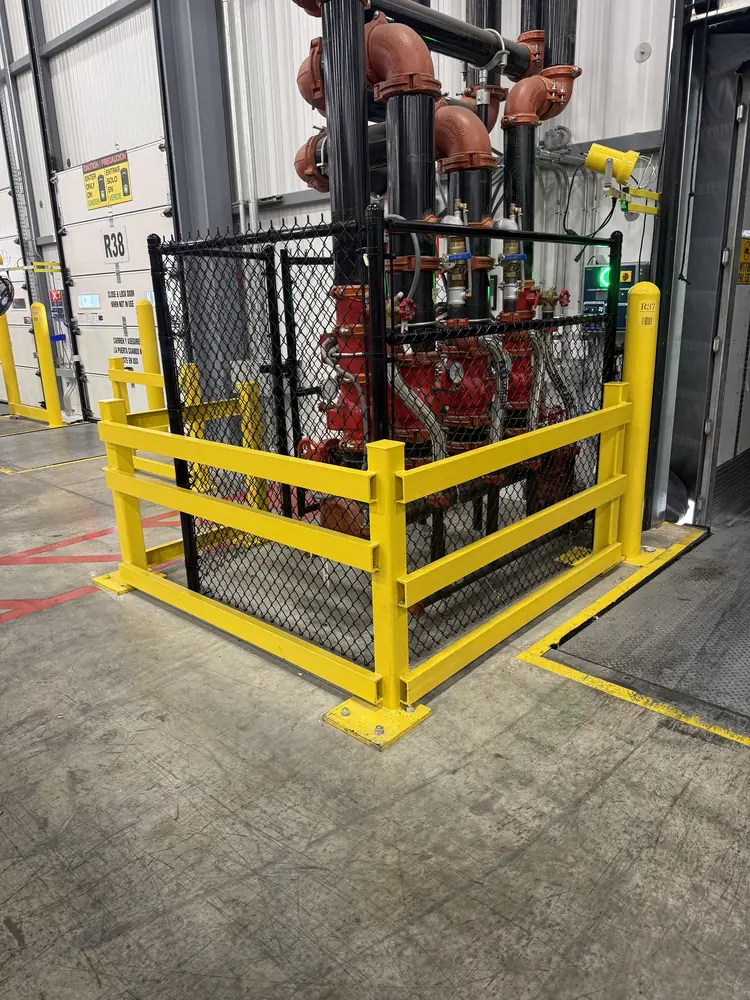 Chain link guard enclosure with yellow safety bollards