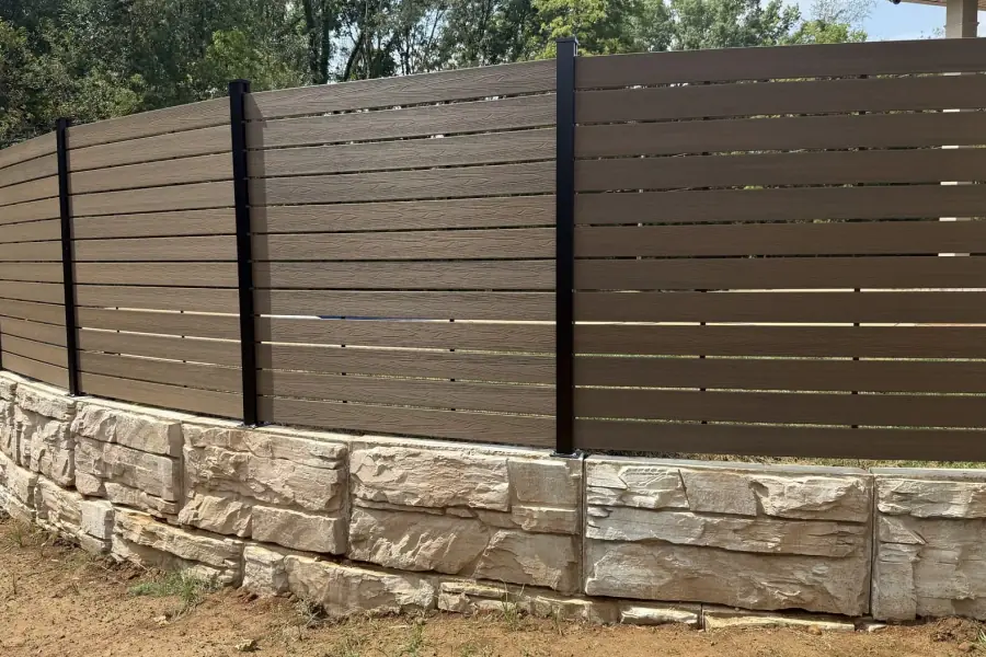 Horizontal stained privacy fence on a stone wall