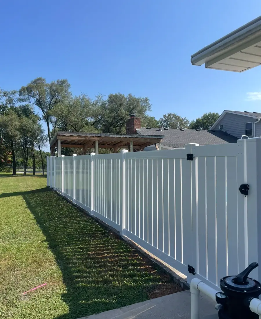 White vinyl privacy fence with gate beside a home